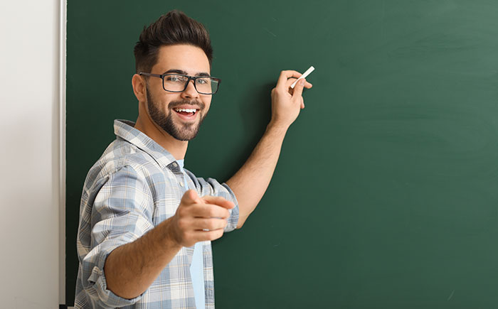 Male teacher writing on blackboard in classroom