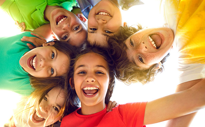 Group of happy little children playing together, having fun, huddling, looking down and smiling